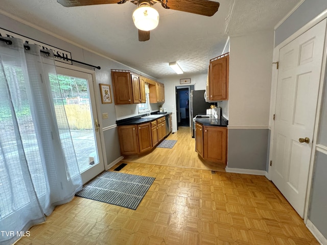 kitchen with appliances with stainless steel finishes, sink, ornamental molding, ceiling fan, and a textured ceiling