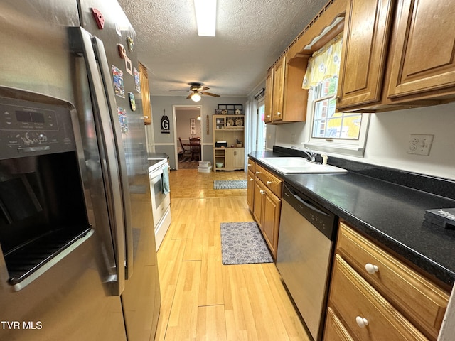 kitchen featuring sink, a textured ceiling, appliances with stainless steel finishes, ceiling fan, and light hardwood / wood-style floors