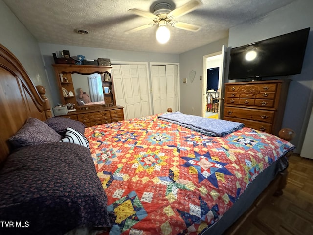 bedroom featuring multiple closets, ceiling fan, dark parquet flooring, and a textured ceiling