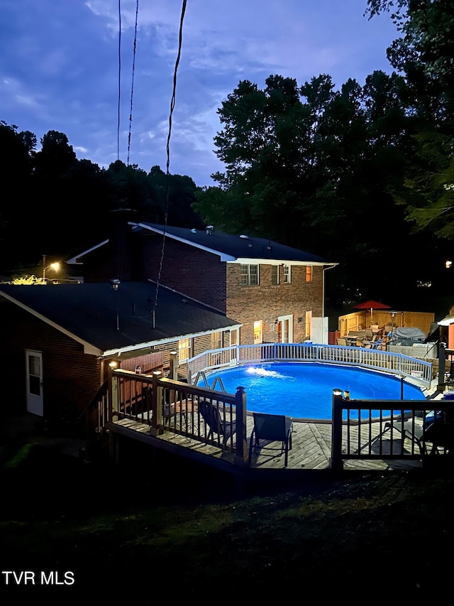 pool at dusk with a wooden deck