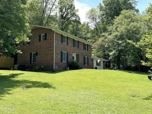 colonial home with cooling unit and a front lawn