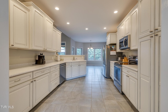 kitchen featuring decorative light fixtures, white cabinetry, light tile patterned flooring, stainless steel appliances, and sink