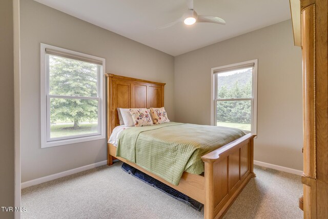 carpeted bedroom featuring multiple windows and ceiling fan