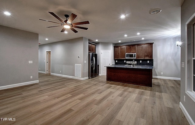 kitchen featuring ceiling fan, light wood-type flooring, black fridge with ice dispenser, and a kitchen island with sink