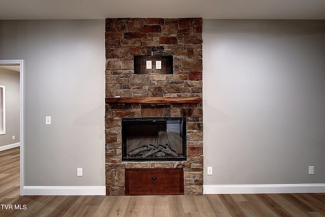 room details featuring wood-type flooring and a stone fireplace