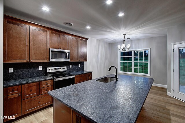 kitchen featuring sink, stainless steel appliances, decorative backsplash, and light hardwood / wood-style floors