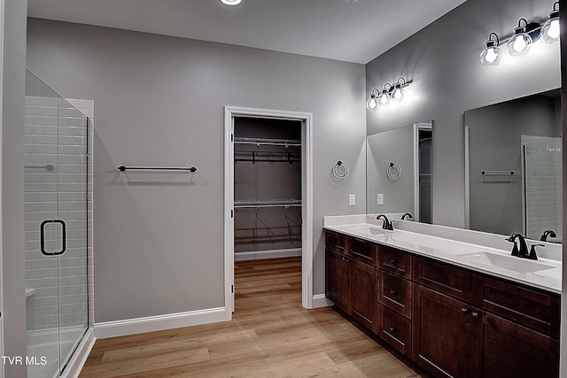 bathroom with hardwood / wood-style floors, a shower with shower door, and dual vanity