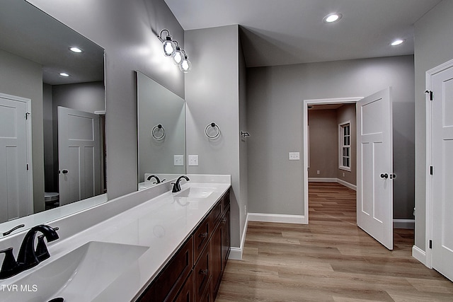 bathroom featuring dual vanity, toilet, and hardwood / wood-style floors