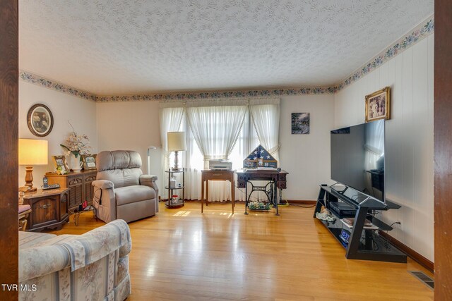 living room featuring light wood-type flooring and a textured ceiling