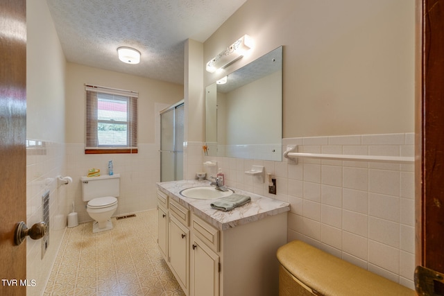 bathroom with toilet, a textured ceiling, tile patterned flooring, and tile walls