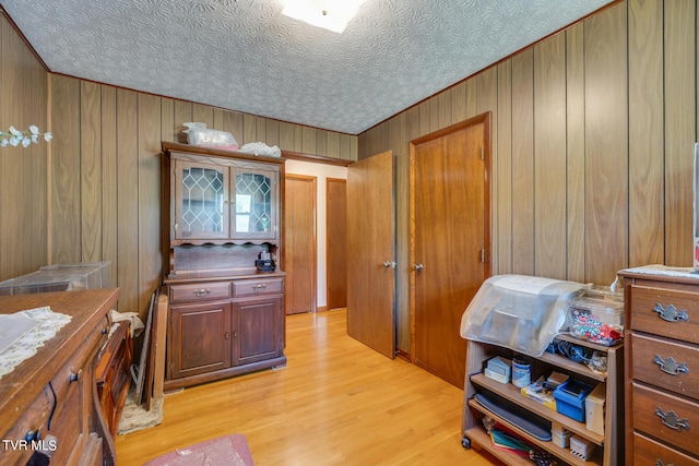 interior space with wood walls, light wood-type flooring, and a textured ceiling