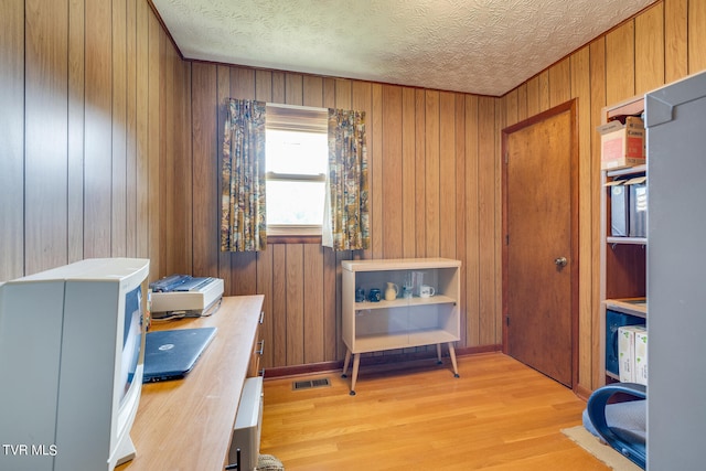 office space with wood walls, a textured ceiling, and light hardwood / wood-style flooring