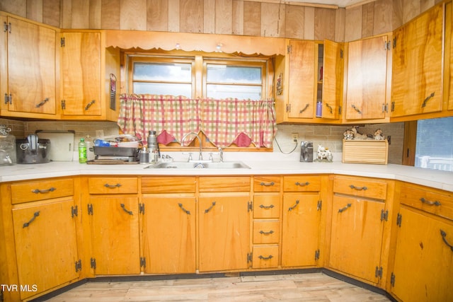 kitchen with brown cabinets, tasteful backsplash, light countertops, and a sink