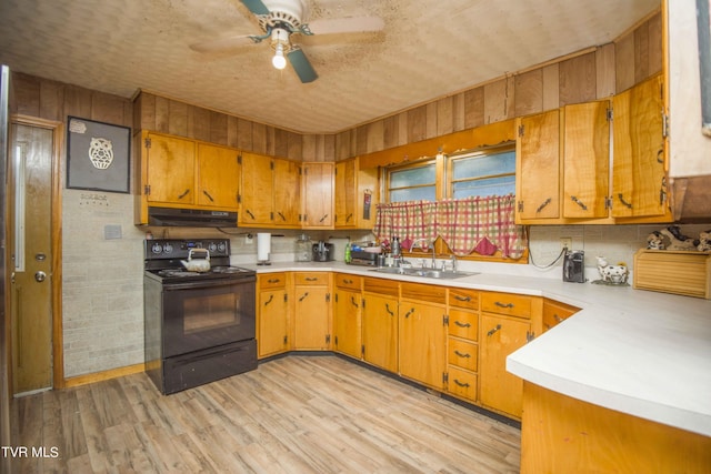 kitchen with black electric range, a sink, light countertops, and under cabinet range hood