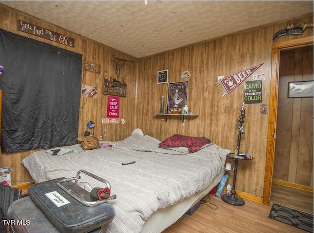 bedroom with wood walls, baseboards, and wood finished floors