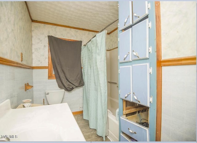 bathroom with wallpapered walls, toilet, and tile walls