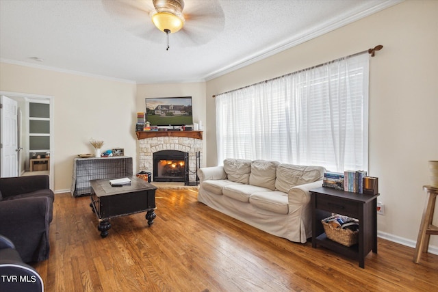 living area featuring crown molding, a fireplace, a textured ceiling, and wood finished floors