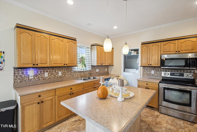 kitchen with a kitchen island, appliances with stainless steel finishes, light countertops, washer and dryer, and a sink