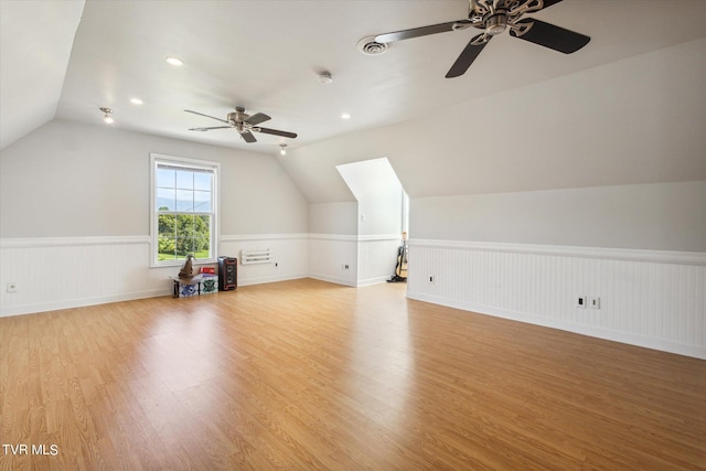 bonus room with a wainscoted wall, vaulted ceiling, and light wood-style floors