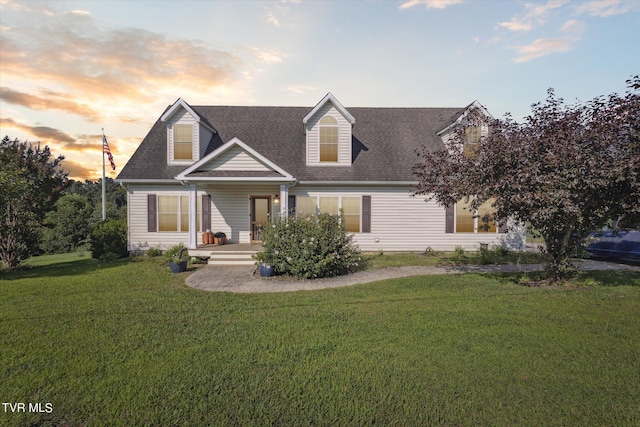 cape cod house featuring a shingled roof and a yard