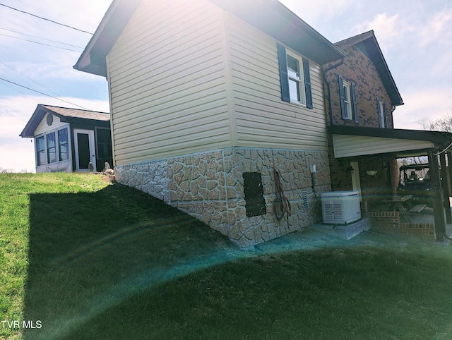 view of side of home with central AC unit and a yard