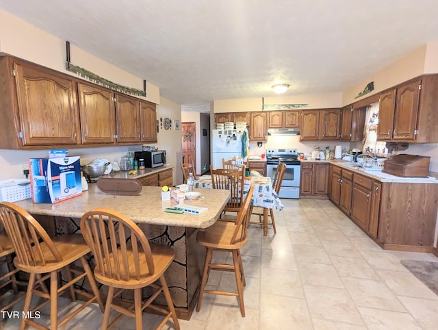 kitchen featuring white refrigerator, electric stove, sink, a kitchen bar, and light tile patterned floors