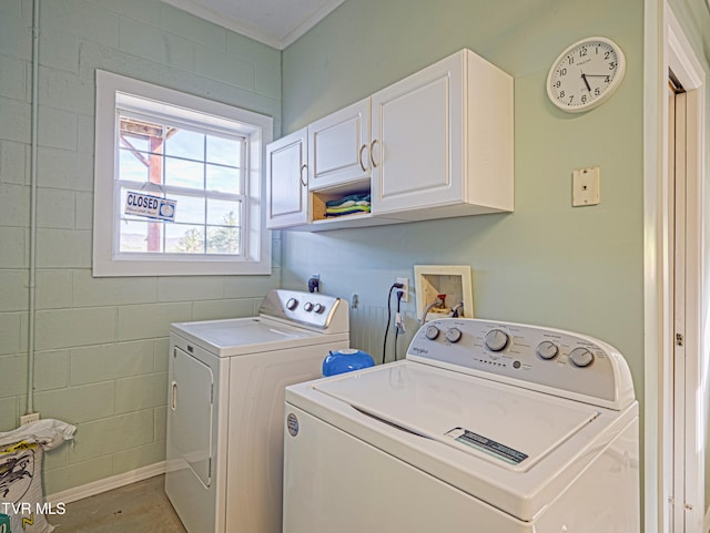 clothes washing area featuring washing machine and dryer, cabinet space, and crown molding