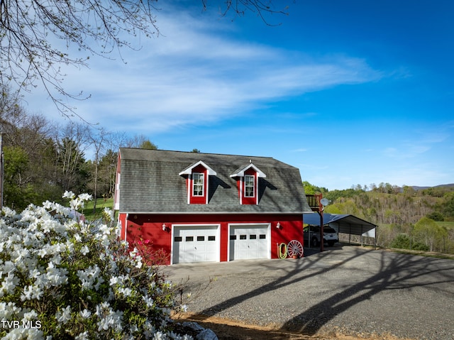 garage featuring a carport, a detached garage, and driveway