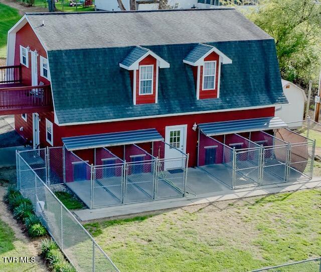 rear view of house with a shingled roof, a lawn, fence, and a gambrel roof