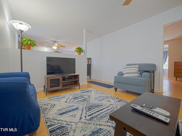 living room featuring baseboards, a ceiling fan, and wood finished floors