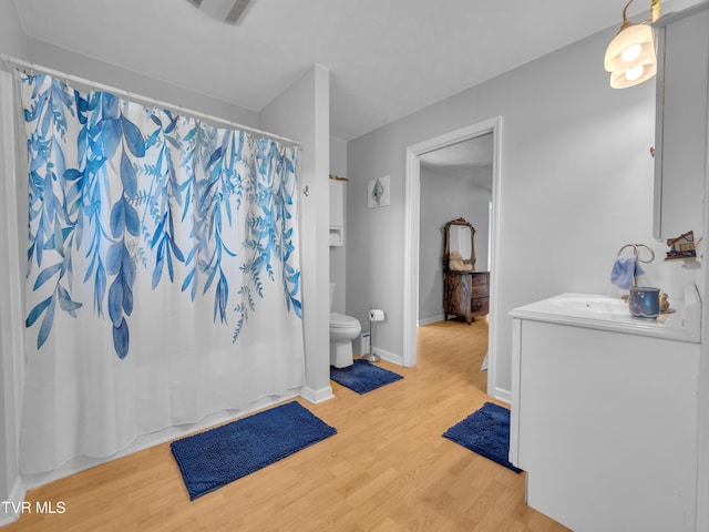 full bathroom featuring a shower with shower curtain, toilet, vanity, wood finished floors, and baseboards