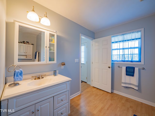 bathroom featuring plenty of natural light, baseboards, wood finished floors, and vanity