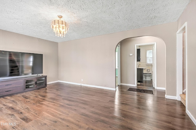 living room with dark wood-type flooring, an inviting chandelier, and a textured ceiling