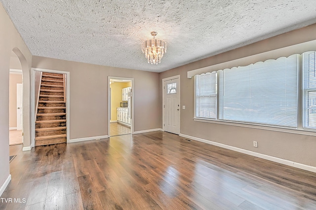 foyer entrance with a notable chandelier, dark hardwood / wood-style floors, and a textured ceiling