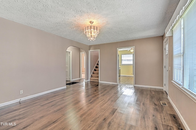 spare room with dark hardwood / wood-style flooring, a textured ceiling, and a notable chandelier