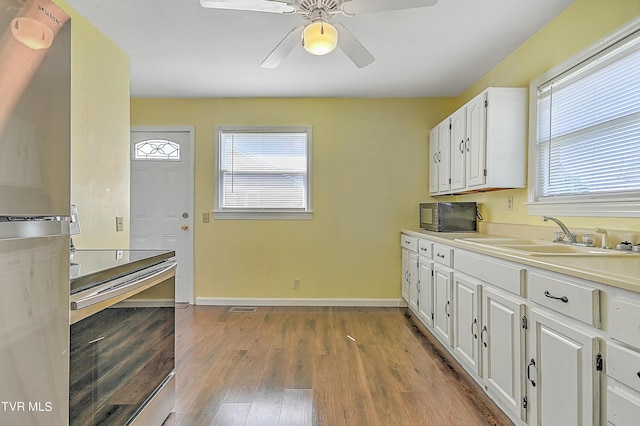 kitchen with appliances with stainless steel finishes, sink, wood-type flooring, and white cabinets