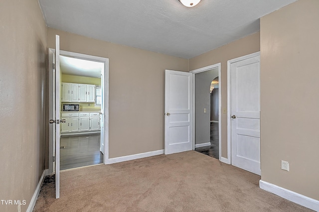 unfurnished bedroom with ensuite bathroom and light carpet