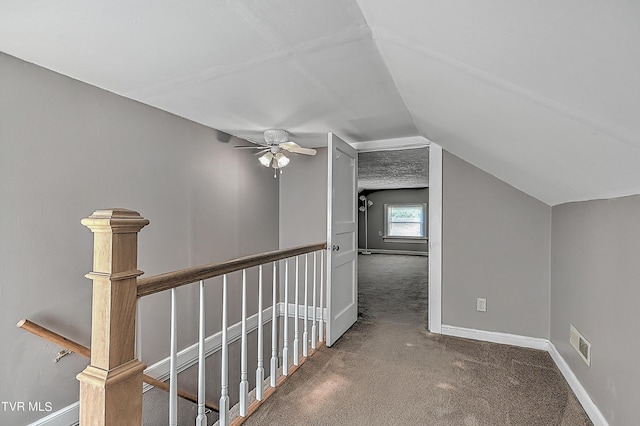 hall with lofted ceiling and dark carpet