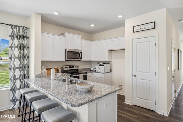 kitchen featuring appliances with stainless steel finishes, dark hardwood / wood-style flooring, white cabinets, and kitchen peninsula