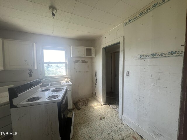 kitchen with white cabinets, light tile patterned floors, and white electric range