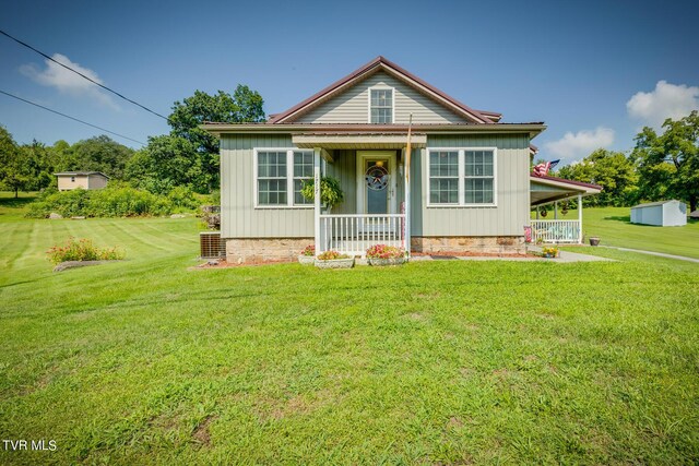 view of front of property featuring a porch, a front lawn, and a storage shed