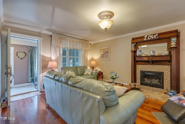 living area with ornamental molding, a tiled fireplace, dark wood finished floors, and baseboards