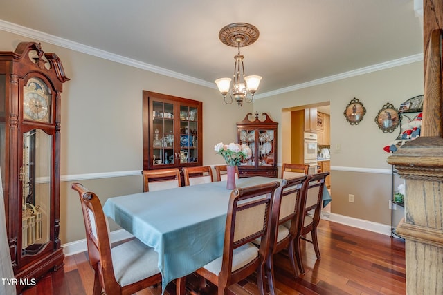 dining space featuring baseboards, a notable chandelier, ornamental molding, and dark wood-type flooring