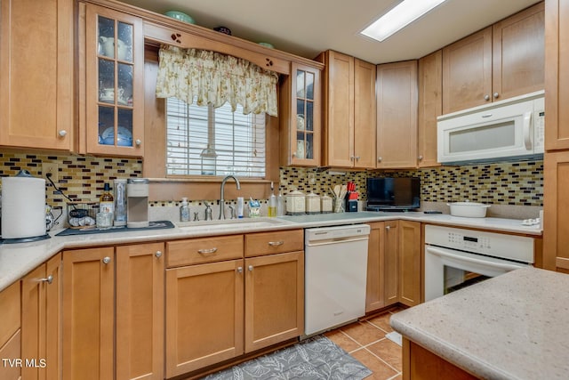 kitchen with white appliances, a sink, backsplash, and light tile patterned floors