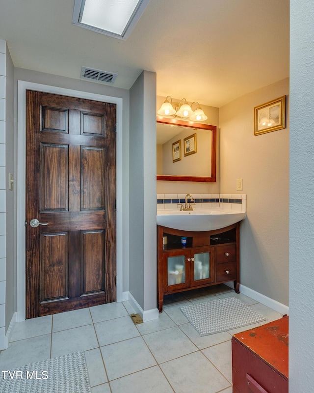 bathroom with baseboards, vanity, visible vents, and tile patterned floors