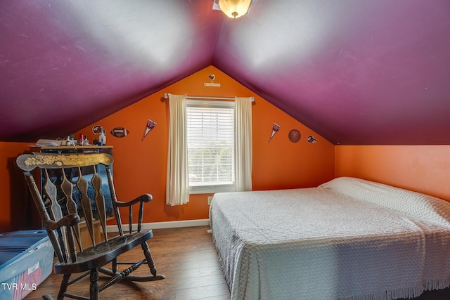 bedroom with vaulted ceiling, baseboards, and wood finished floors