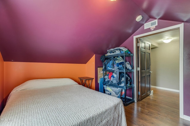 bedroom featuring lofted ceiling, visible vents, baseboards, and wood finished floors