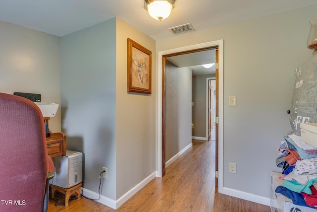 corridor with wood finished floors, visible vents, and baseboards