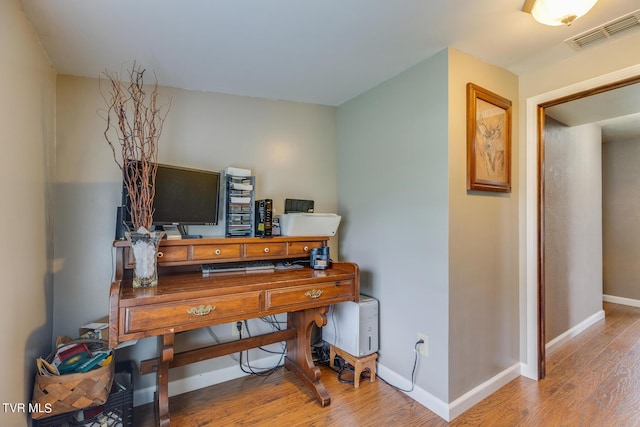 office space featuring visible vents, baseboards, and wood finished floors