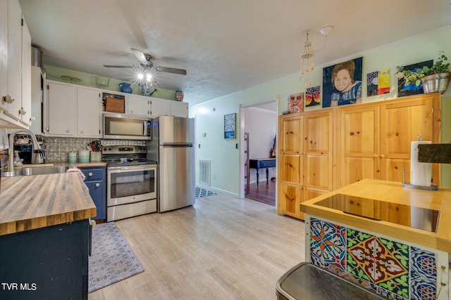 kitchen featuring butcher block counters, stainless steel appliances, sink, white cabinets, and light hardwood / wood-style floors